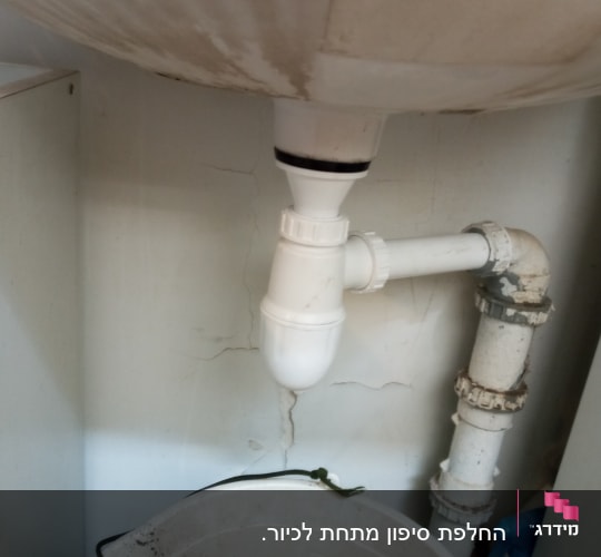 צינור ניקוז לבן מתחת לכיור עם דלי
